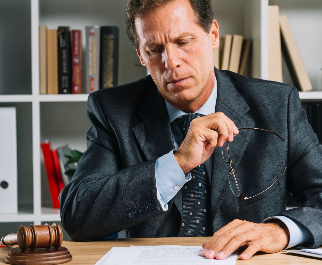 serious mature lawyer reading document desk courtr Proces działu spadku - kiedy i jak skorzystać z pomocy adwokata?